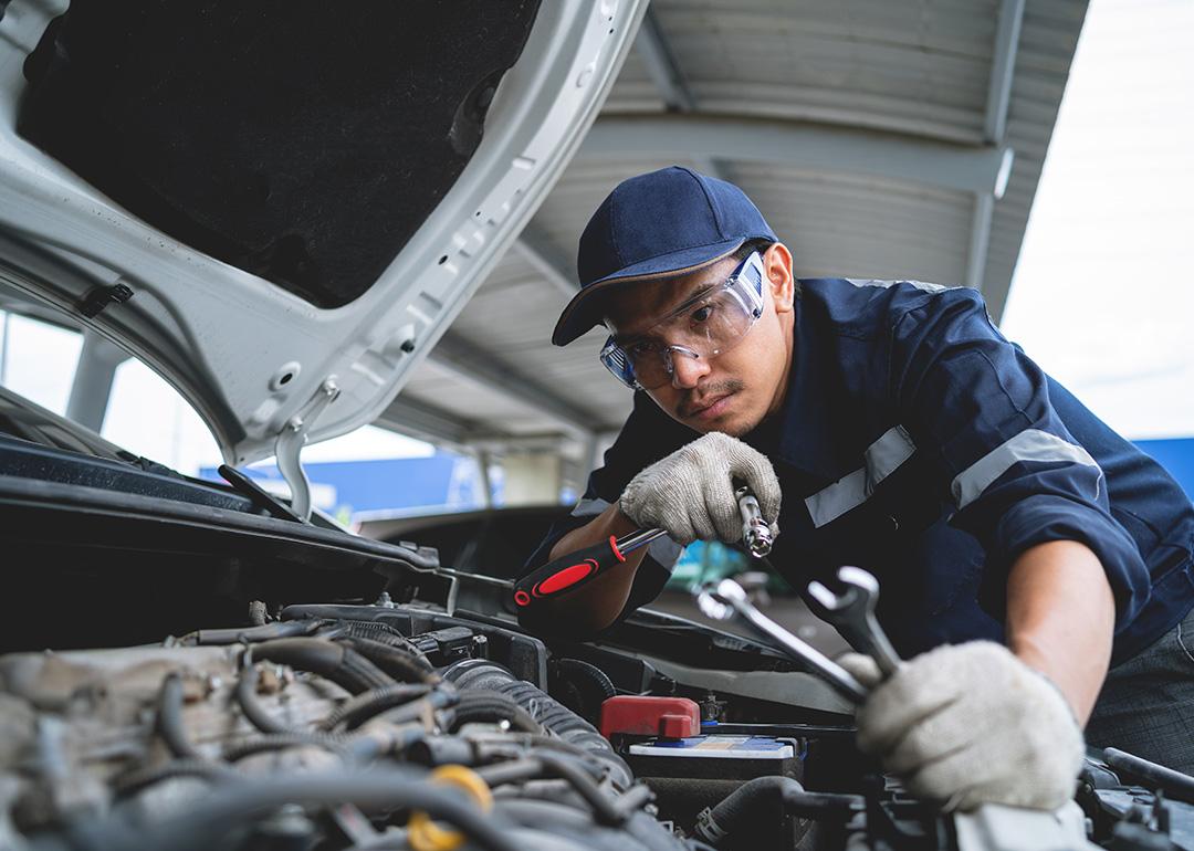 A mechanic working on a repair and service for a car engine in a garage.