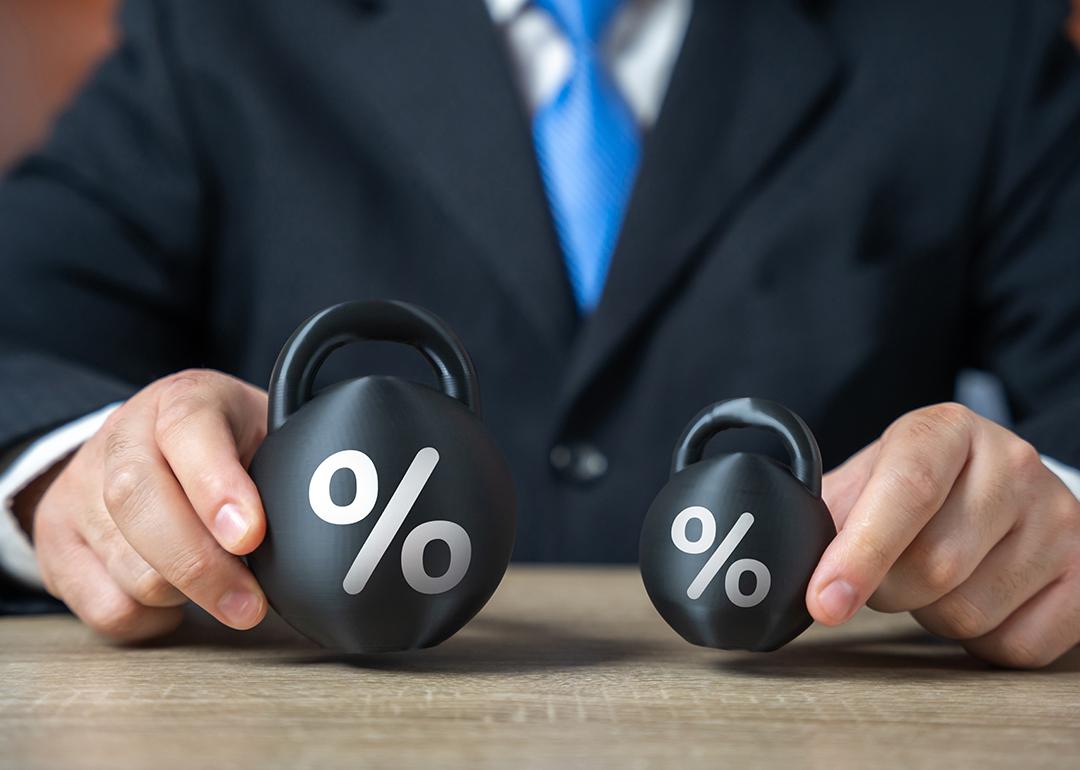 Businessman holding two weights side by side as a concept of concept of debt burden.