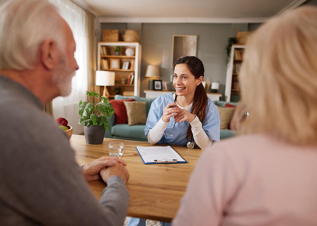 A nurse discussing health issues and plans to elderly patients during a home visit. 