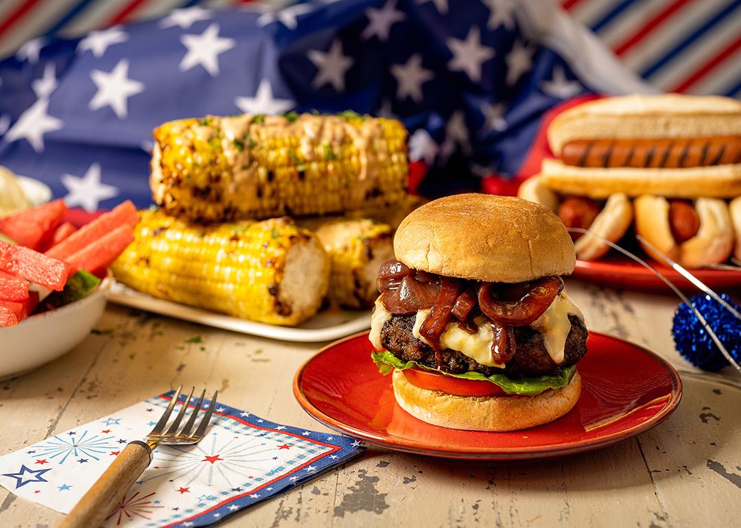 Plates of hamburger, corn, and hotdogs for Fourth of July festivities.
