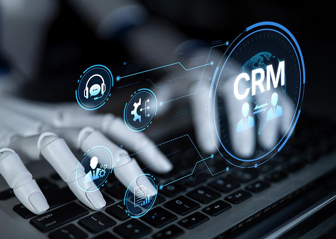 A robot enhancing CRM automation analytics and tools with artificial intelligence from a laptop.