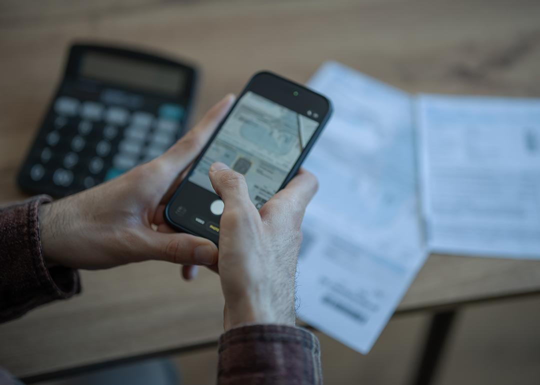 Person holding a smartphone to scan financial documents.