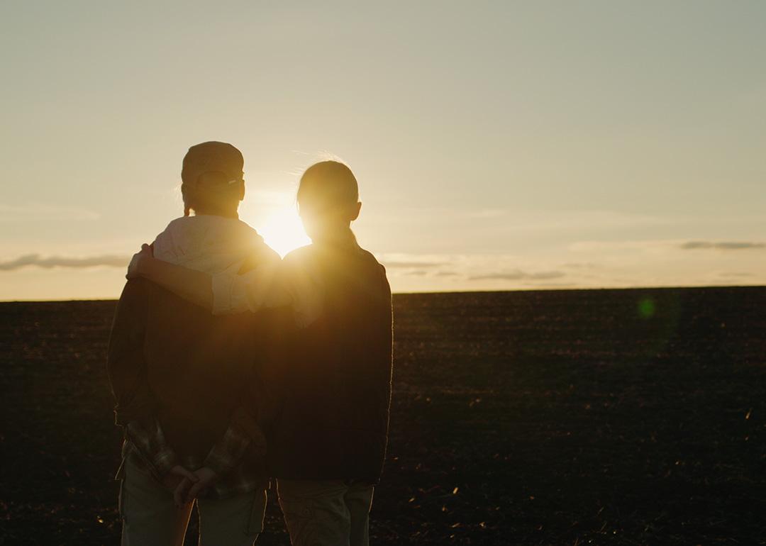 A parent side hugging her child while watching the sunset together.