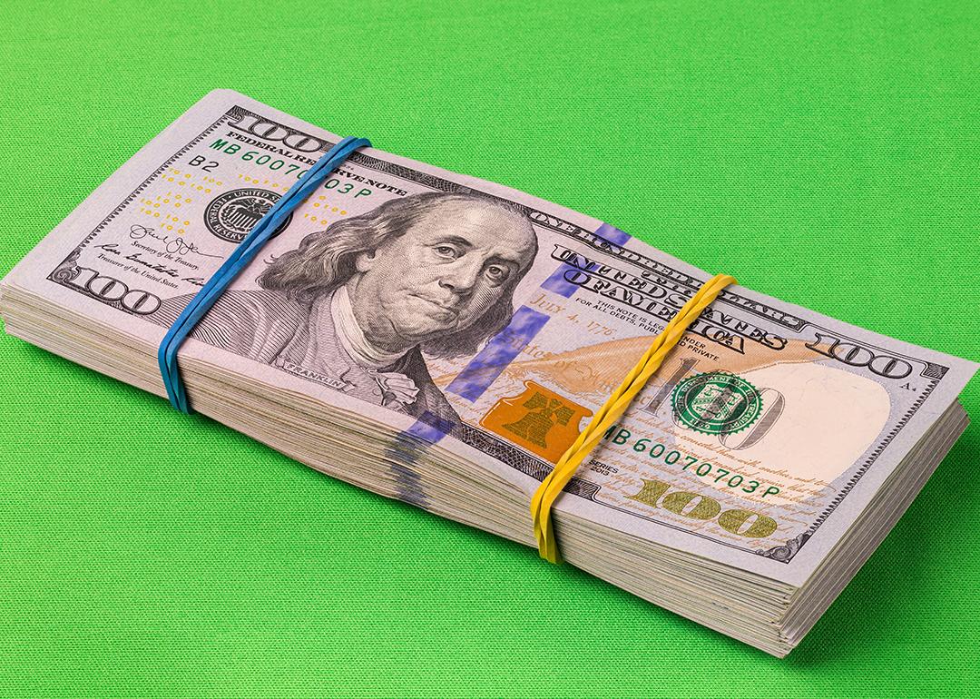 A pack of 10,000 U.S. dollars laid on a striking green background.