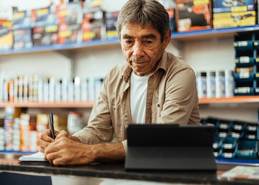 A business owner taking orders at his hardware shop.