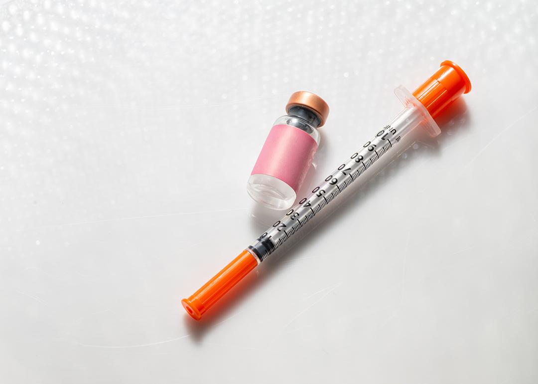 Vial of an injectable compound next to a syringe.