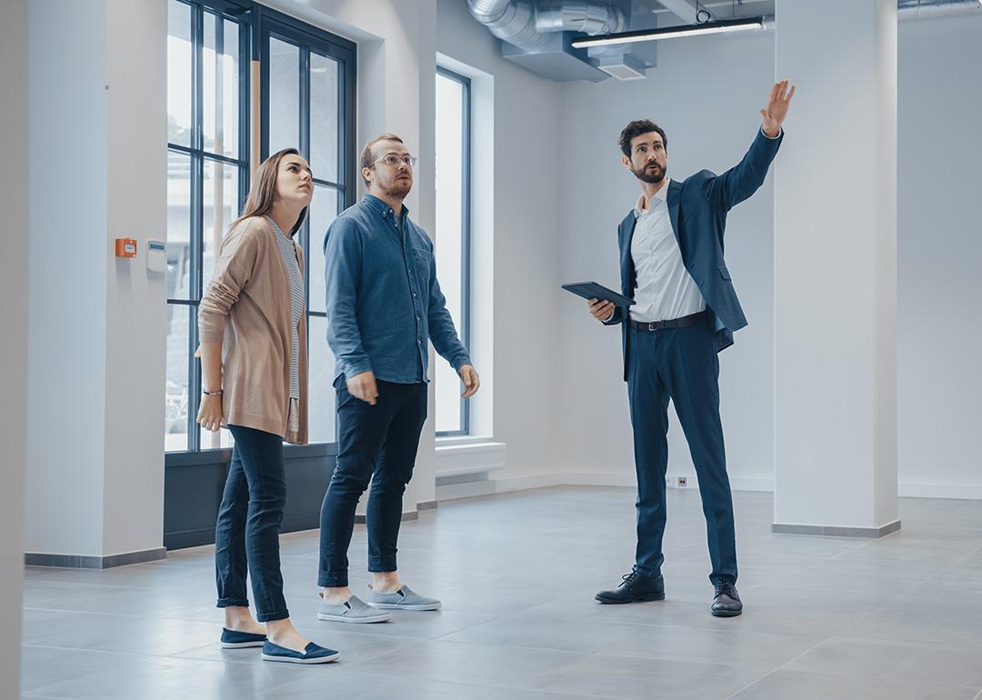 A real estate agent showing an empty office space for rent to clients.