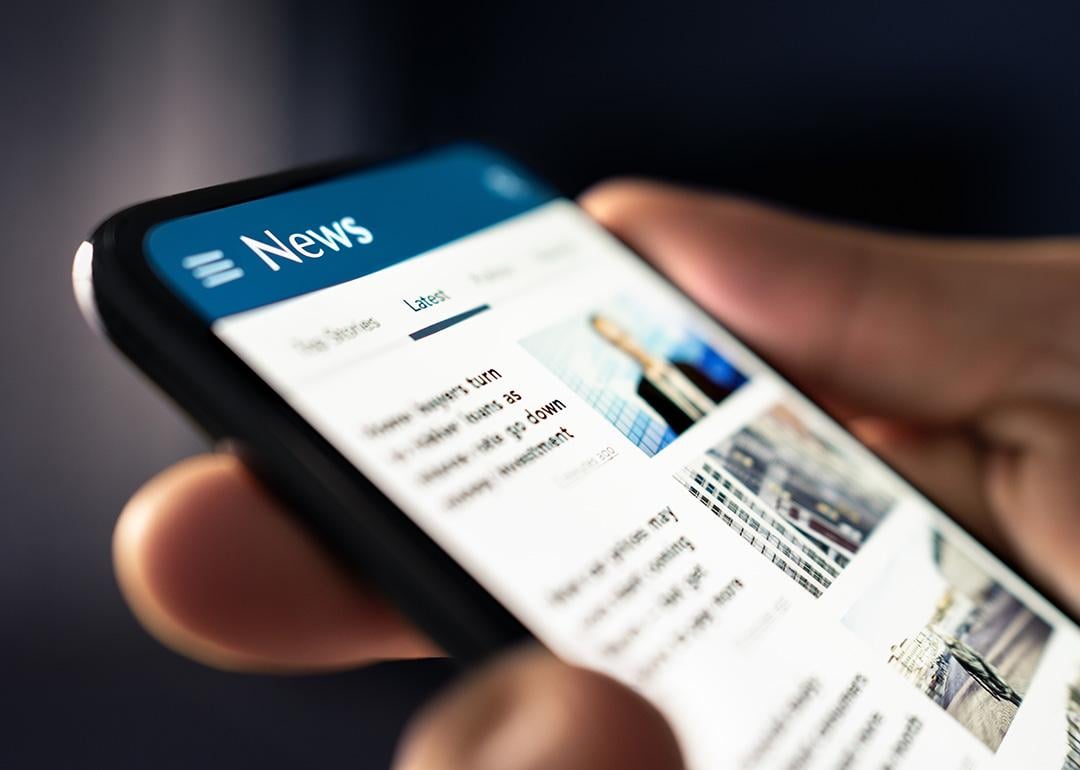 A person reading headlines from a news website online in his smartphone.