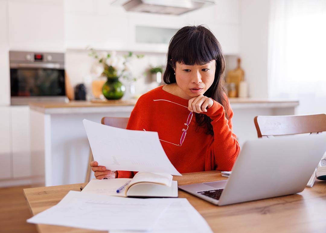 An anxious woman reviewing her bills at home.