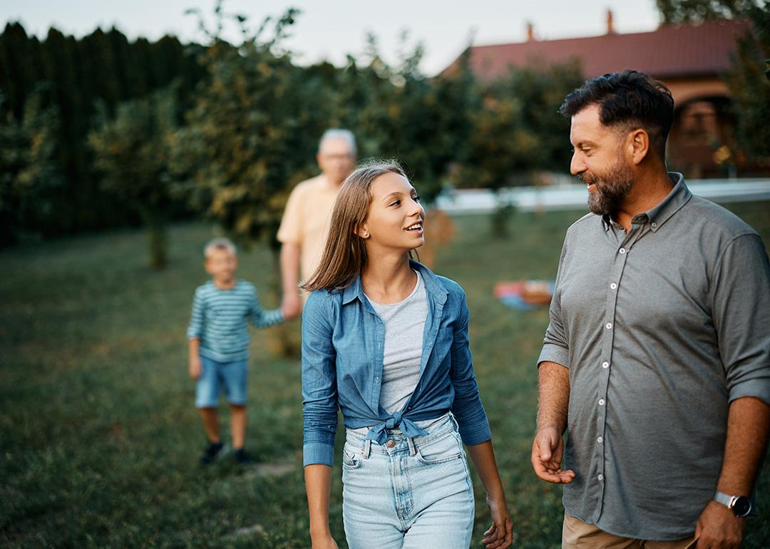 A teenager sharing stories with her father, while walking in the backyard with the family.