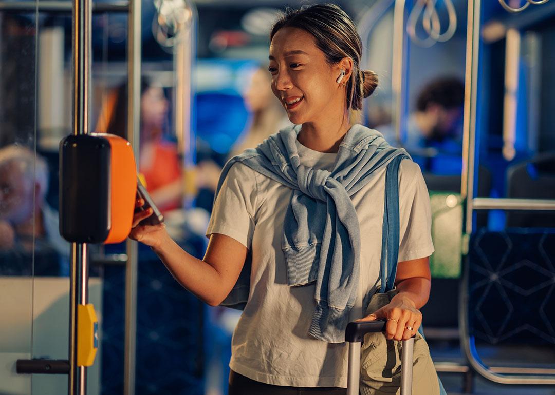 A female tourist paying for bus fare using smartphone NFC technology