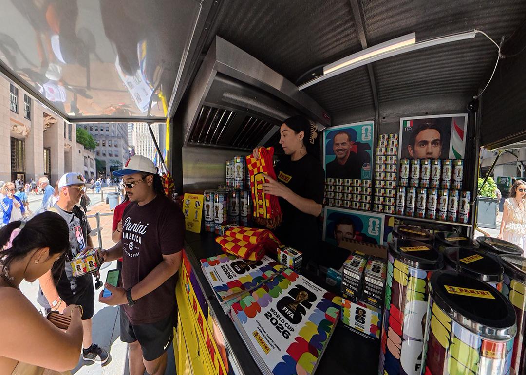Sports fans buying World Cup stickers at a vending cart in New York City, USA.