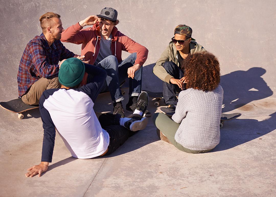 A group of adult skaters hanging out under the sun in a skate park.