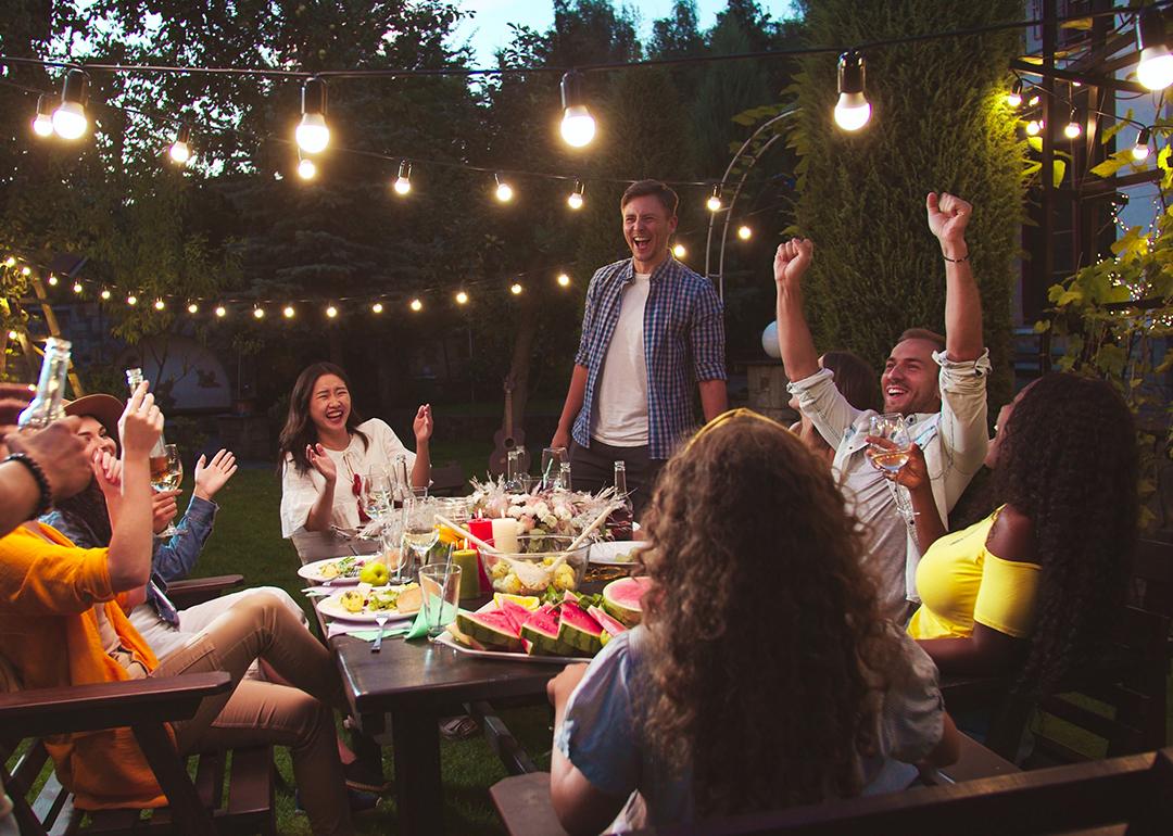 A diverse group of friends having a party at a backyard at night.
