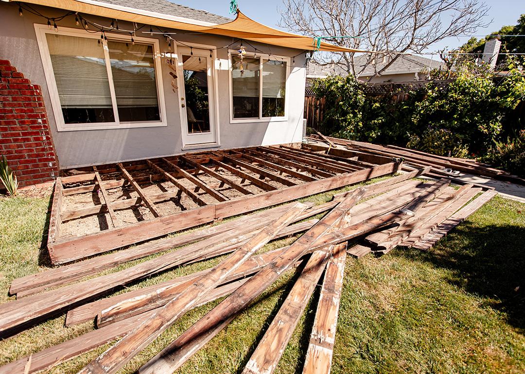 A pile of broken and old wooden lumber laying on the lawn backyard.