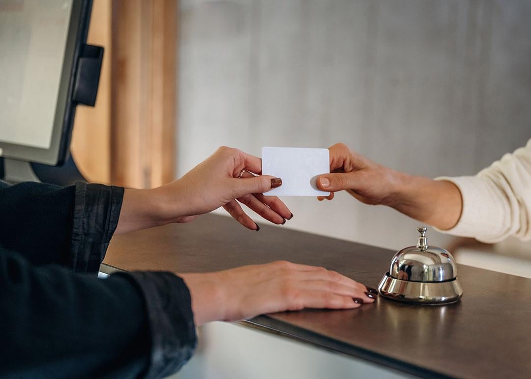 A professional handing credit card over to hotel receptionist to check in.