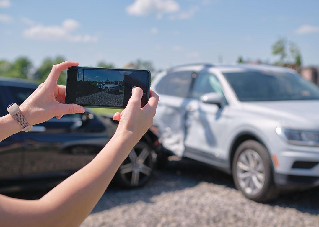A driver taking a photo of their car's damage after an accident.