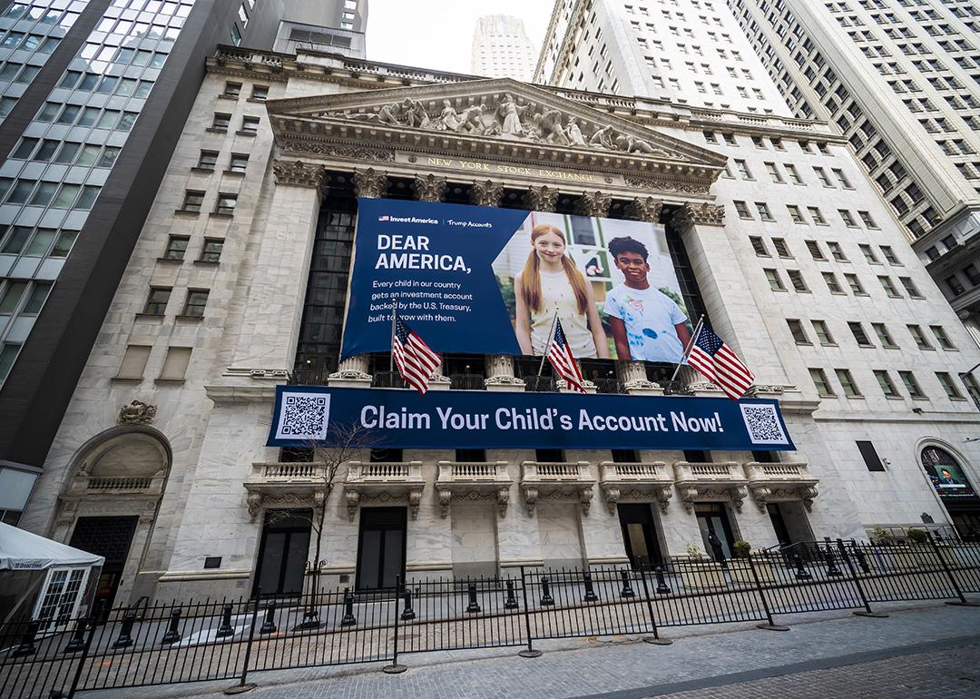 The New York Stock Exchange's facade draped with Invest America | Trump Accounts promotional banners across the building.
