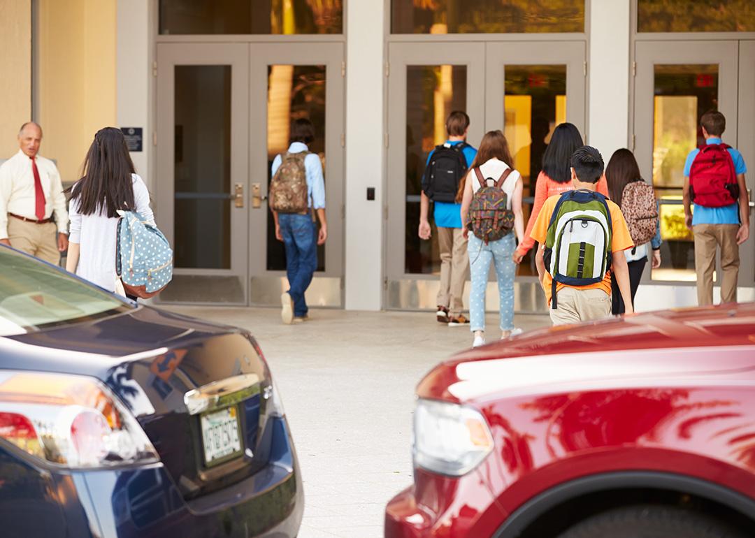High school students being dropped off by their parents at their campus' entrance.