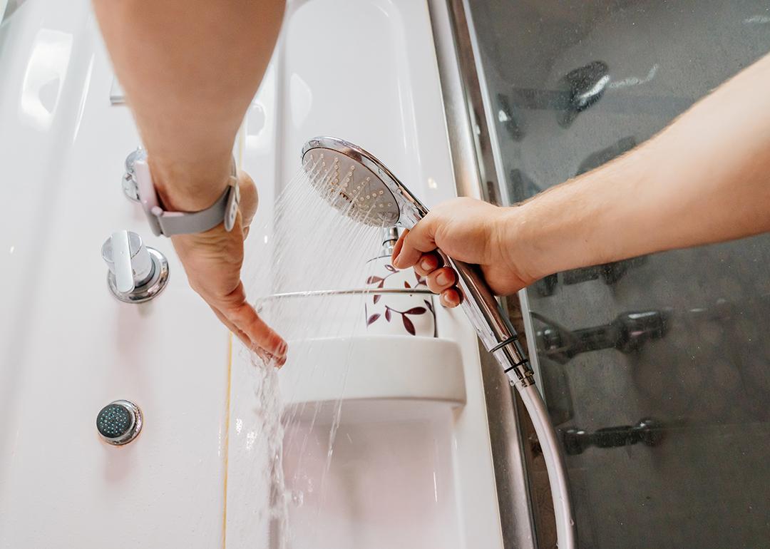 Person testing the water temperature on a shower hose.