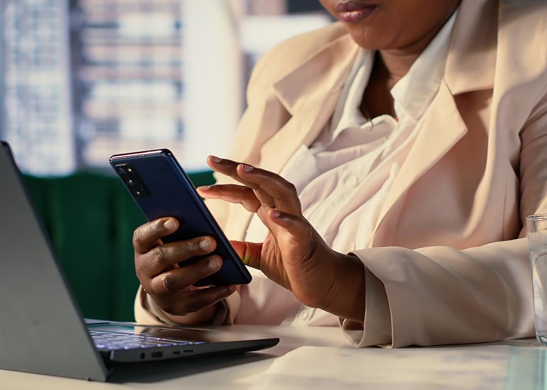 A businesswoman reading text messages from her phone while working in an office.