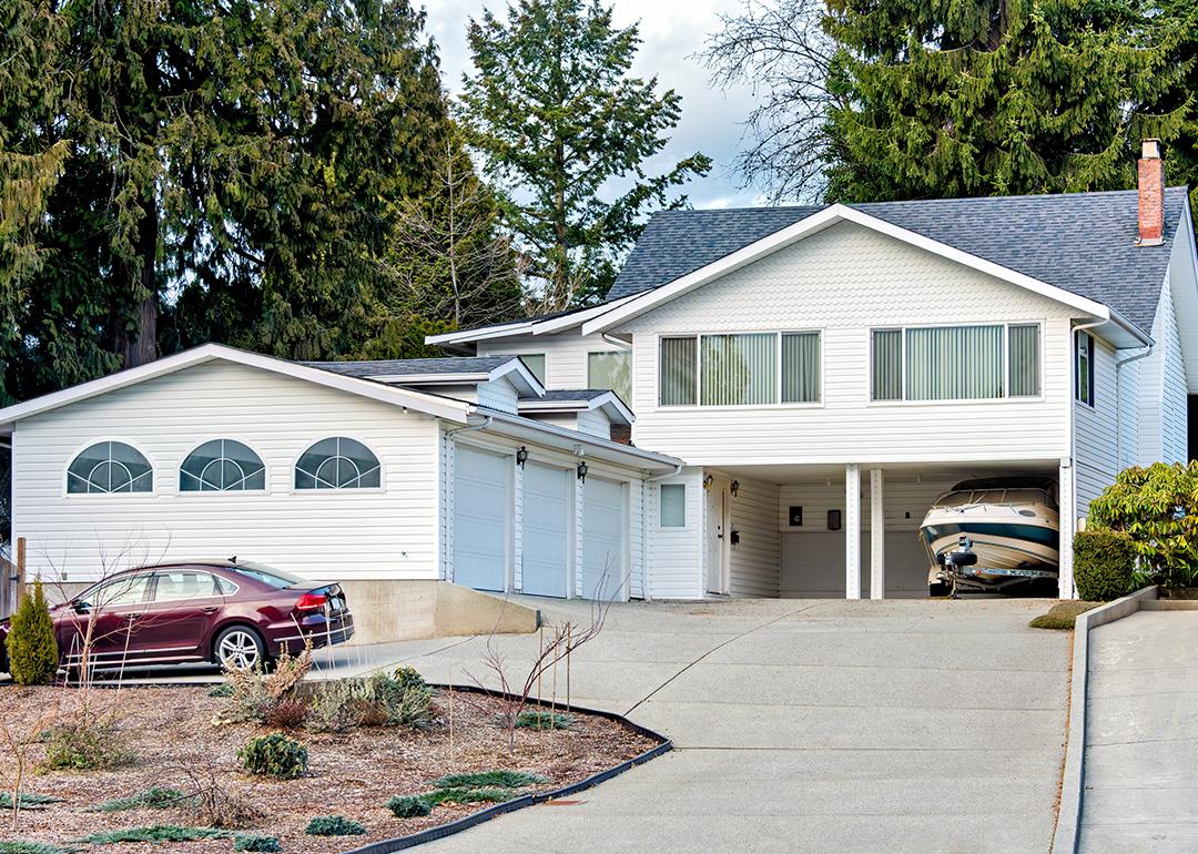 A family house with a private car and a small boat on trailer parked under the carport.