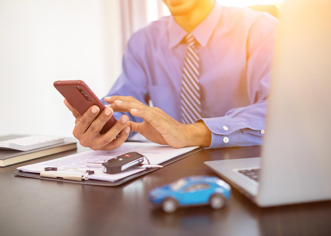 A car dealer calculating monthly car payments for customers from a smartphone.