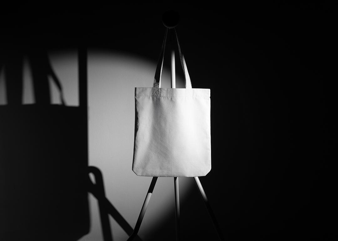 A mockup template of a tote bag on a metal hanger taken in a photo studio.