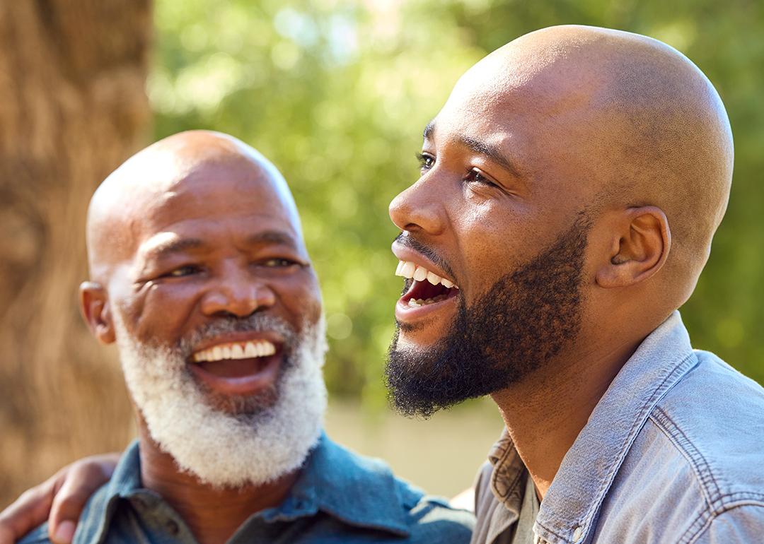 A senior father with his adult son happily engaged in a conversation outdoors.