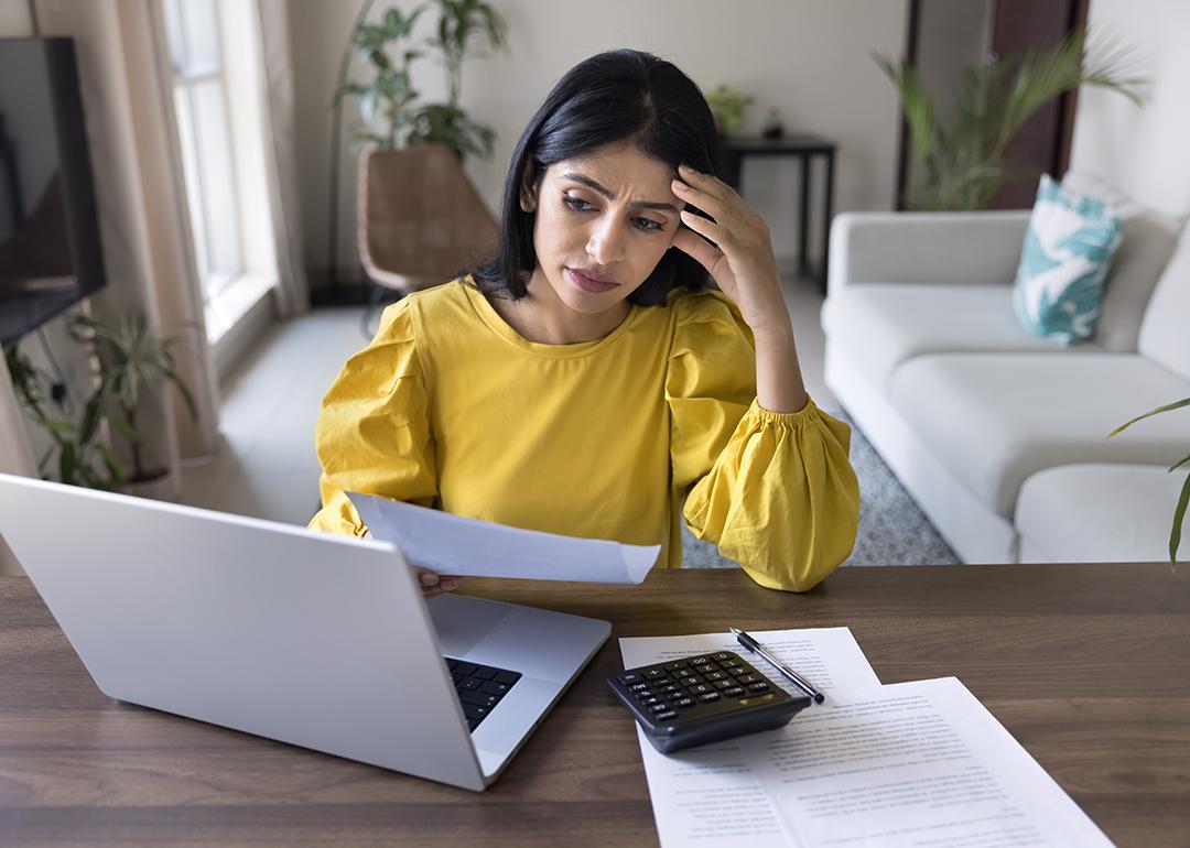 A young adult looking stressed during a personal finance review at home.