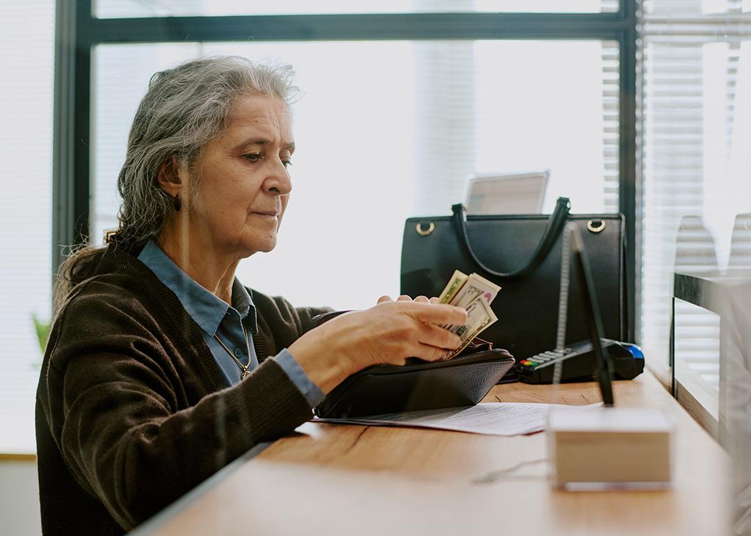 An elderly person preparing cash for a deposit transaction in a bank.