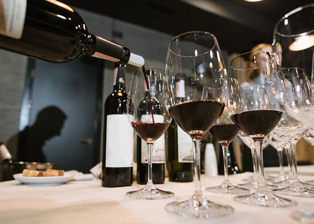 Wine being poured into glasses by a somelier at a restaurant.