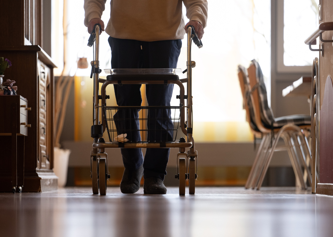 An elderly man using a walker in a nursing home.