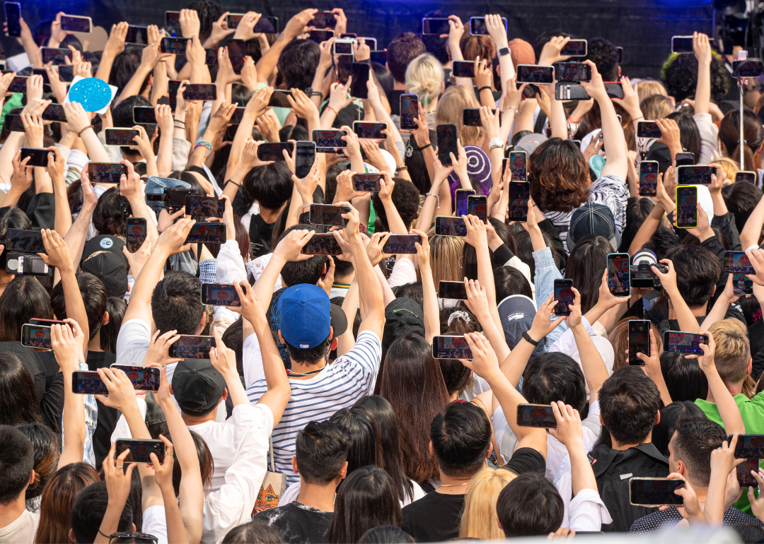 A crowd of people holding phones up in the air.