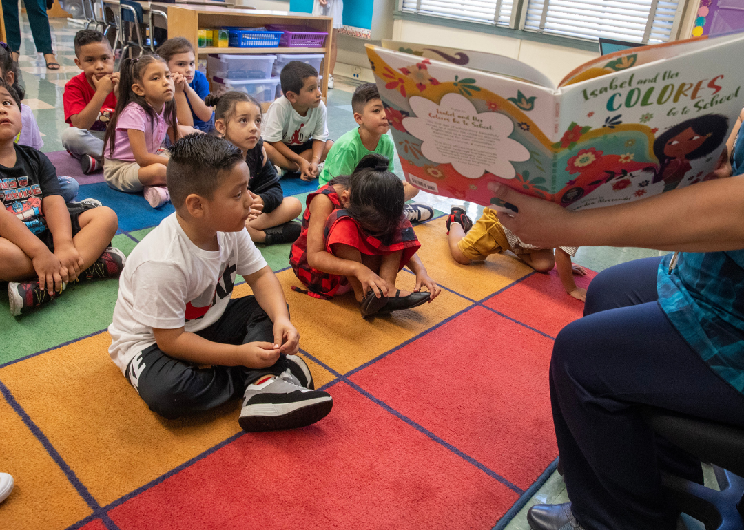 A teacher reading to small children in a classroom.