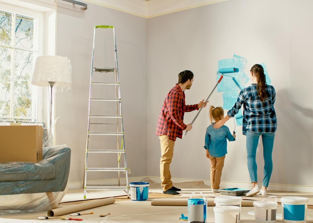 Parents painting the interior of their home with their young daughter