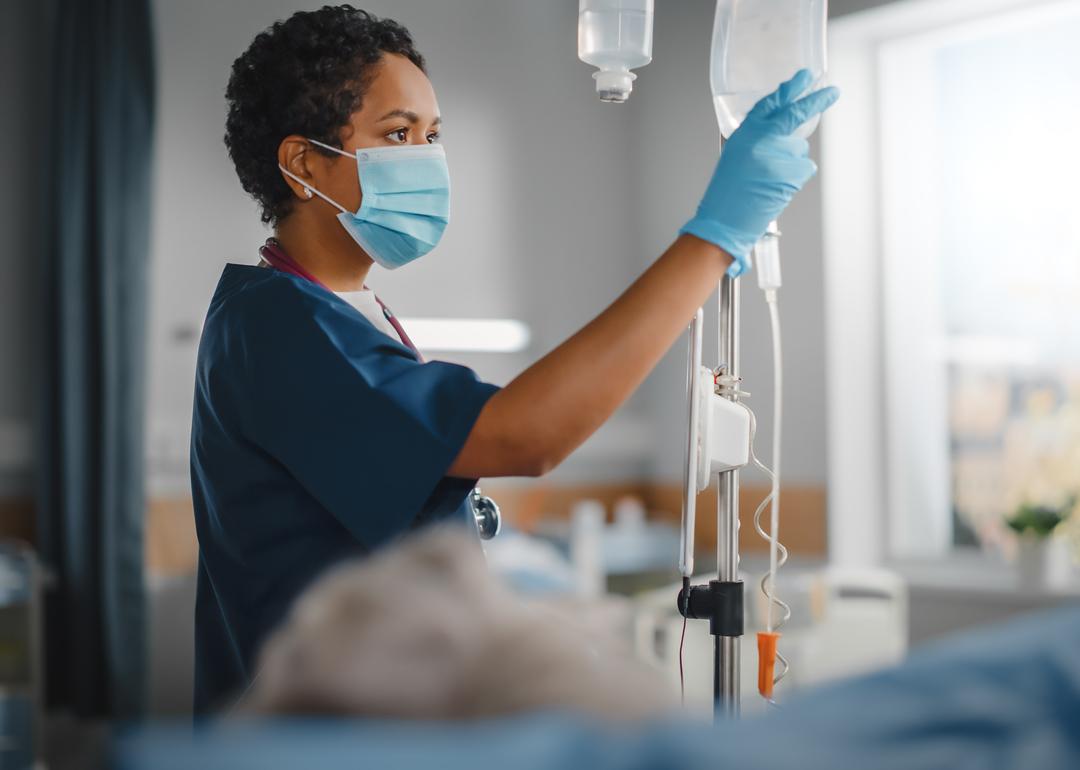 A nurse wearing a face mask checking a patient's vitals