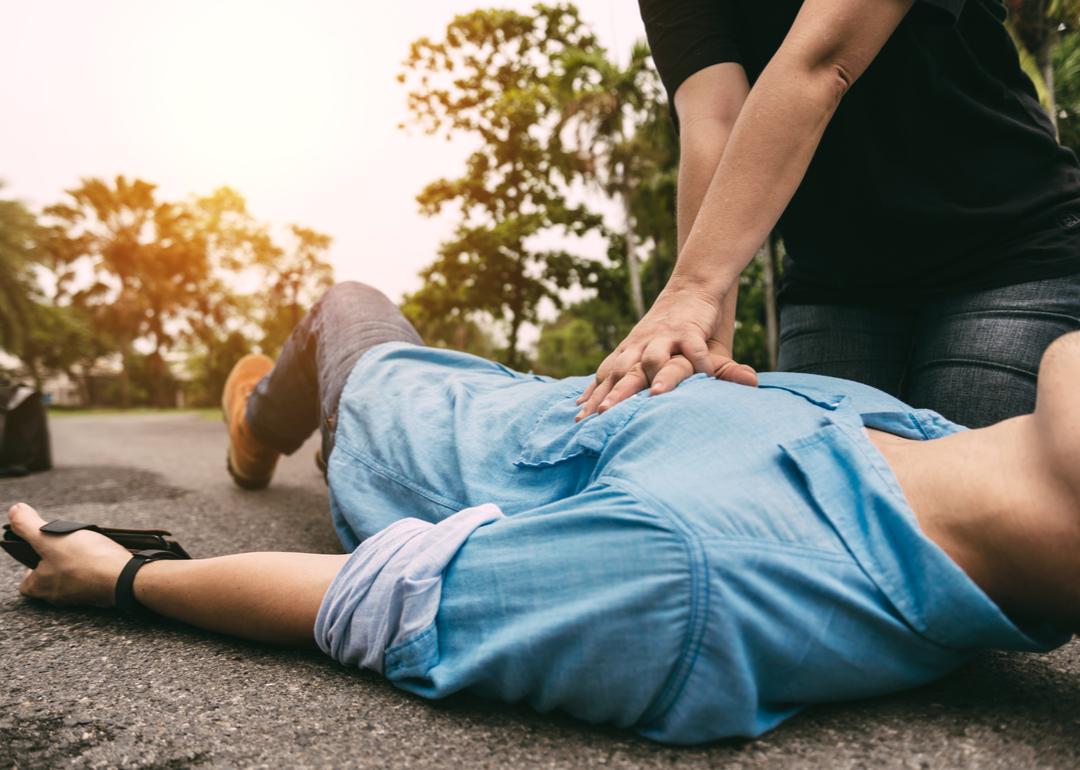 A person performing CPR on a man having a heart attack