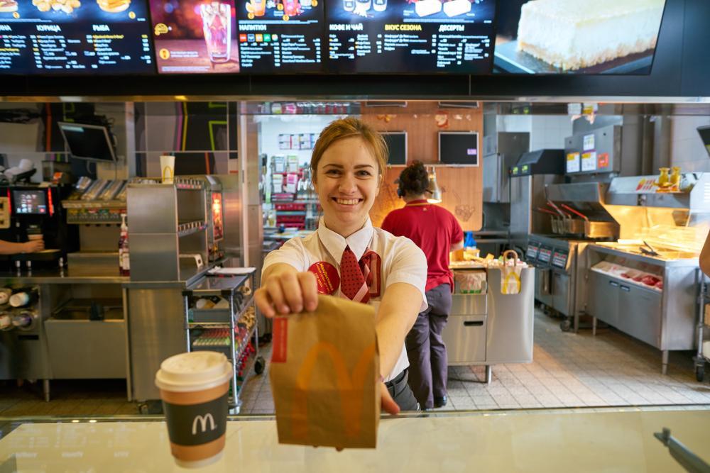 A McDonald's employee hands a bag of food across a counter