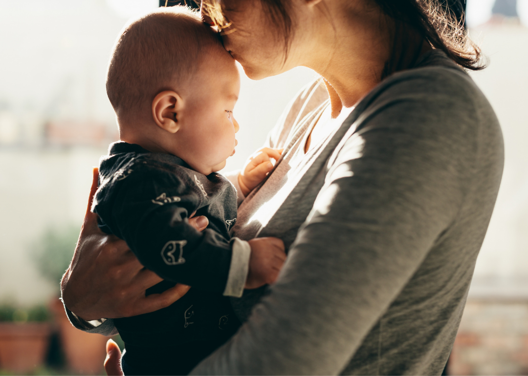 A parent kisses an infant on the head. 