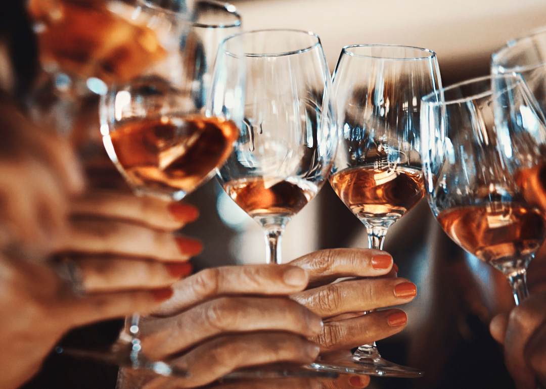 Six hands holding wine glasses for a toast.