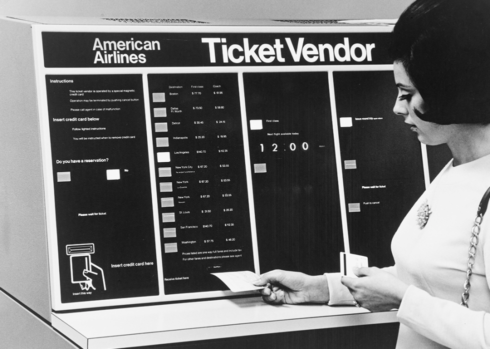 A woman using an American Airlines Ticket Vendor machine.