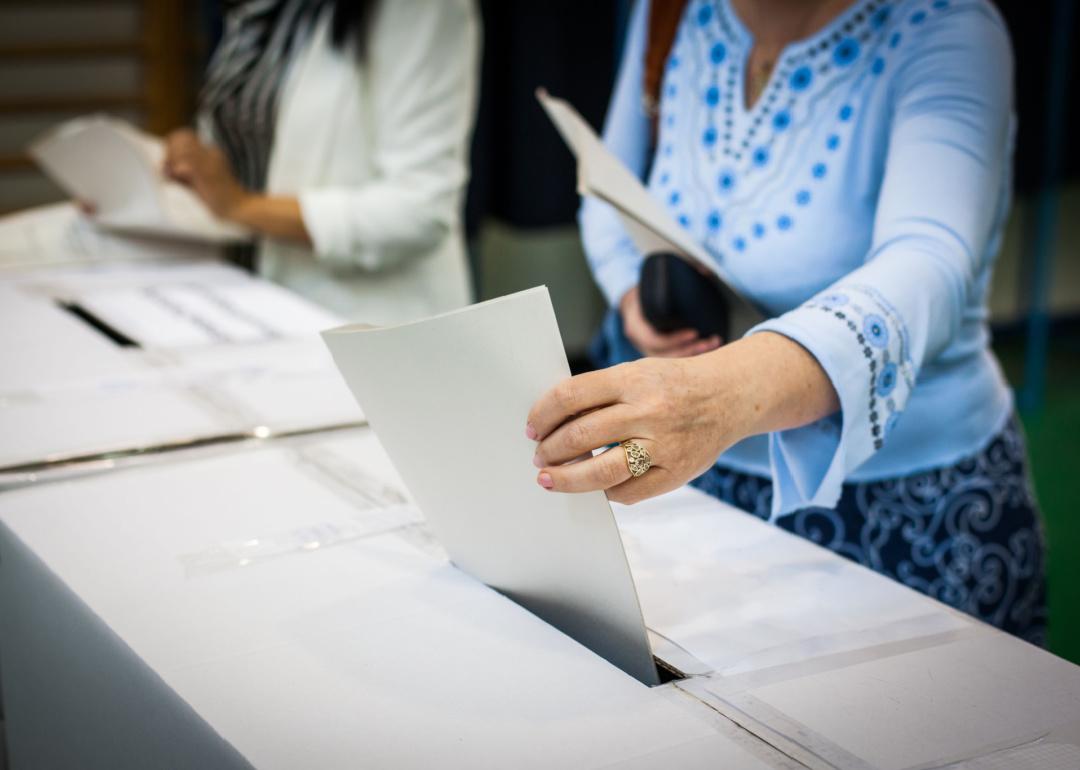 Hand of a person casting a ballot at a polling station