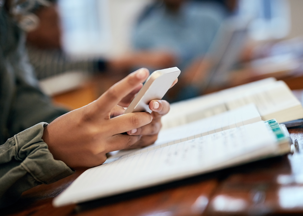 Student at desk using phone.