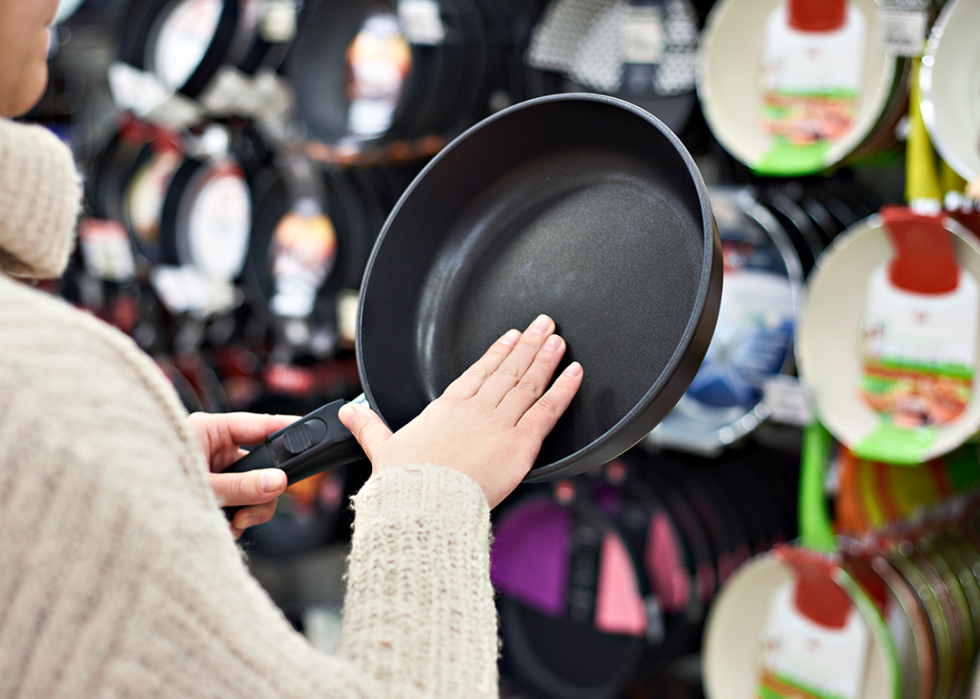 Person choosing nonstick cookware in store.