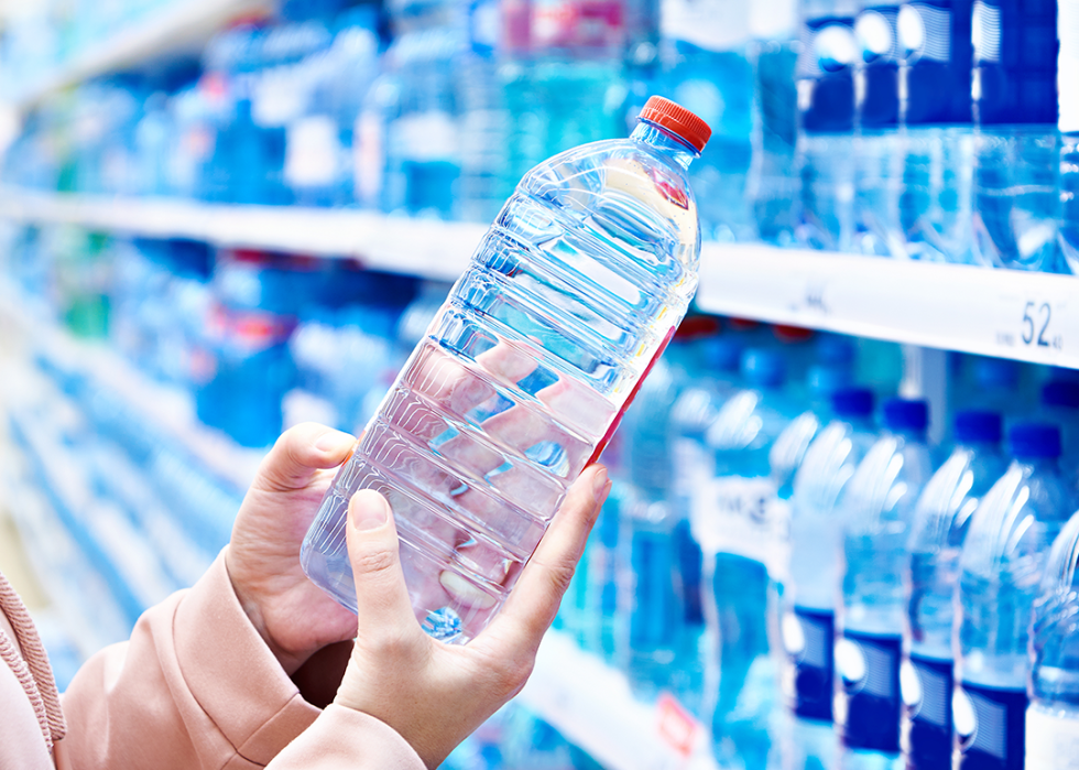 Person holding plastic bottle of water in supermarket.