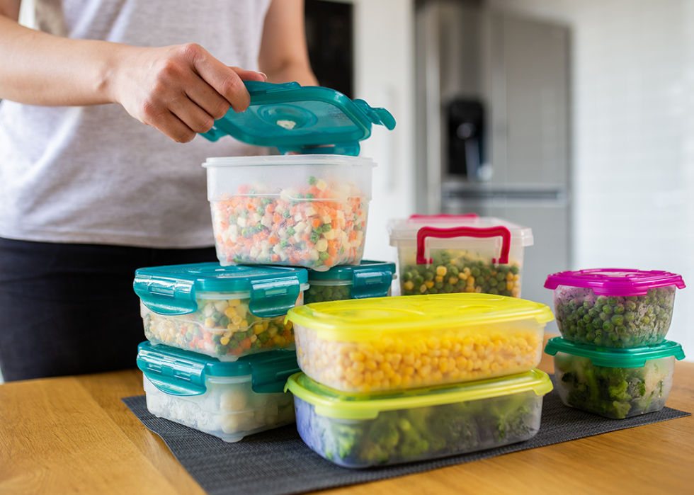 Person preparing plastic containers with frozen vegetables.