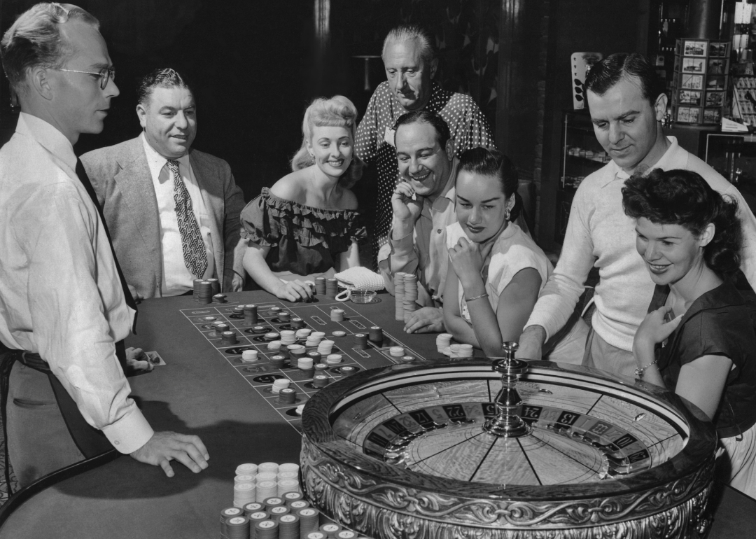 People pose around a roulette table in casino.
