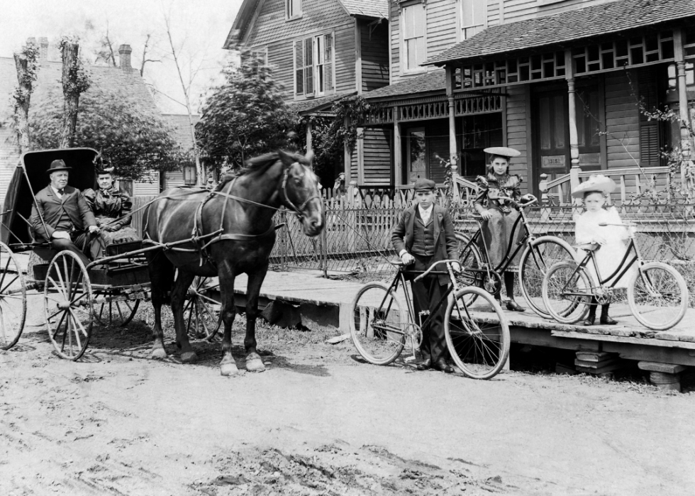 People in street scene with horse and buggy and bicycles