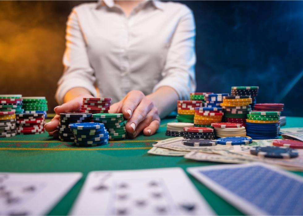 Dealer with chips and cards at poker table.